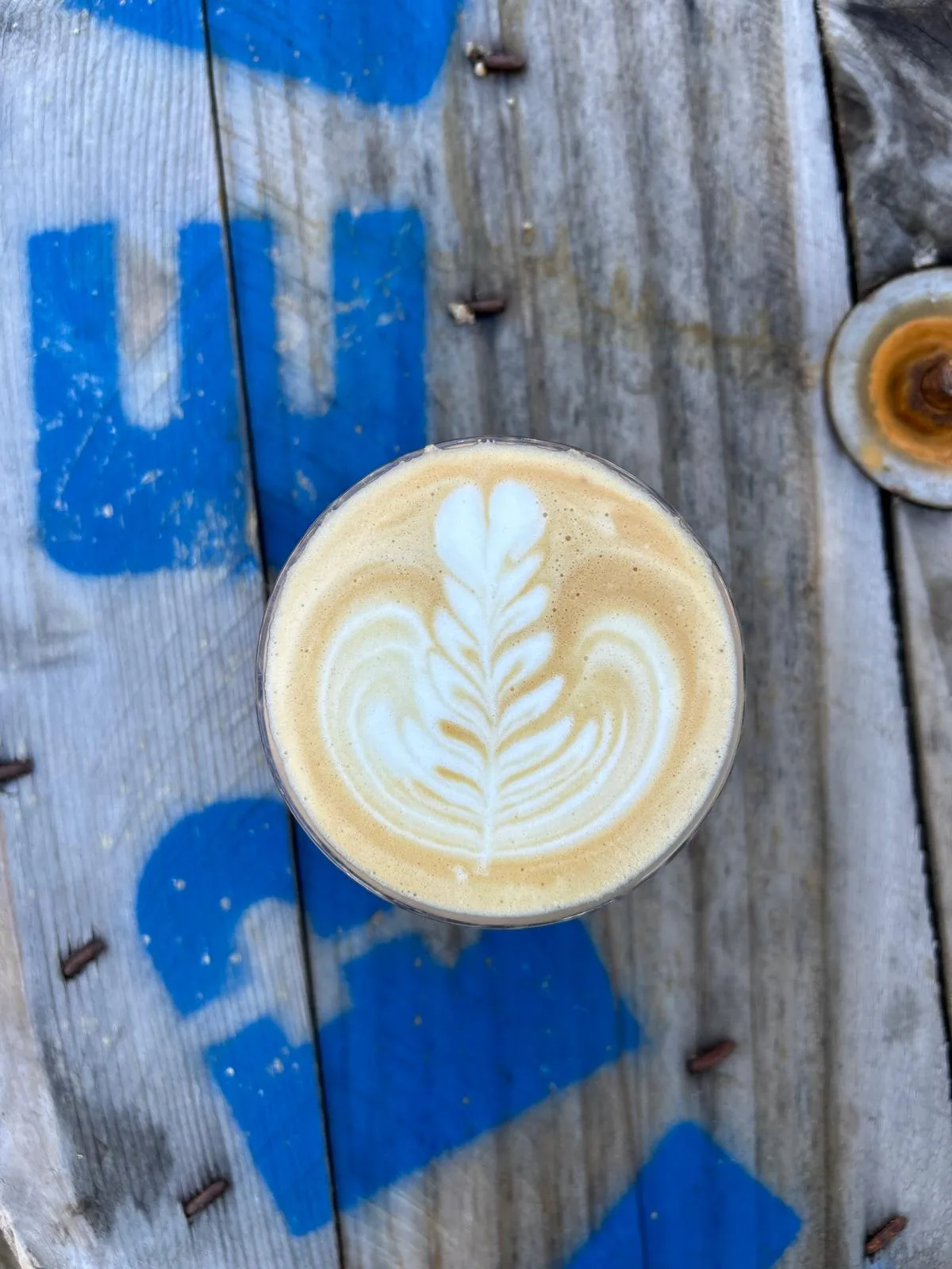 Café latte art servi sur une table en bois bleu
